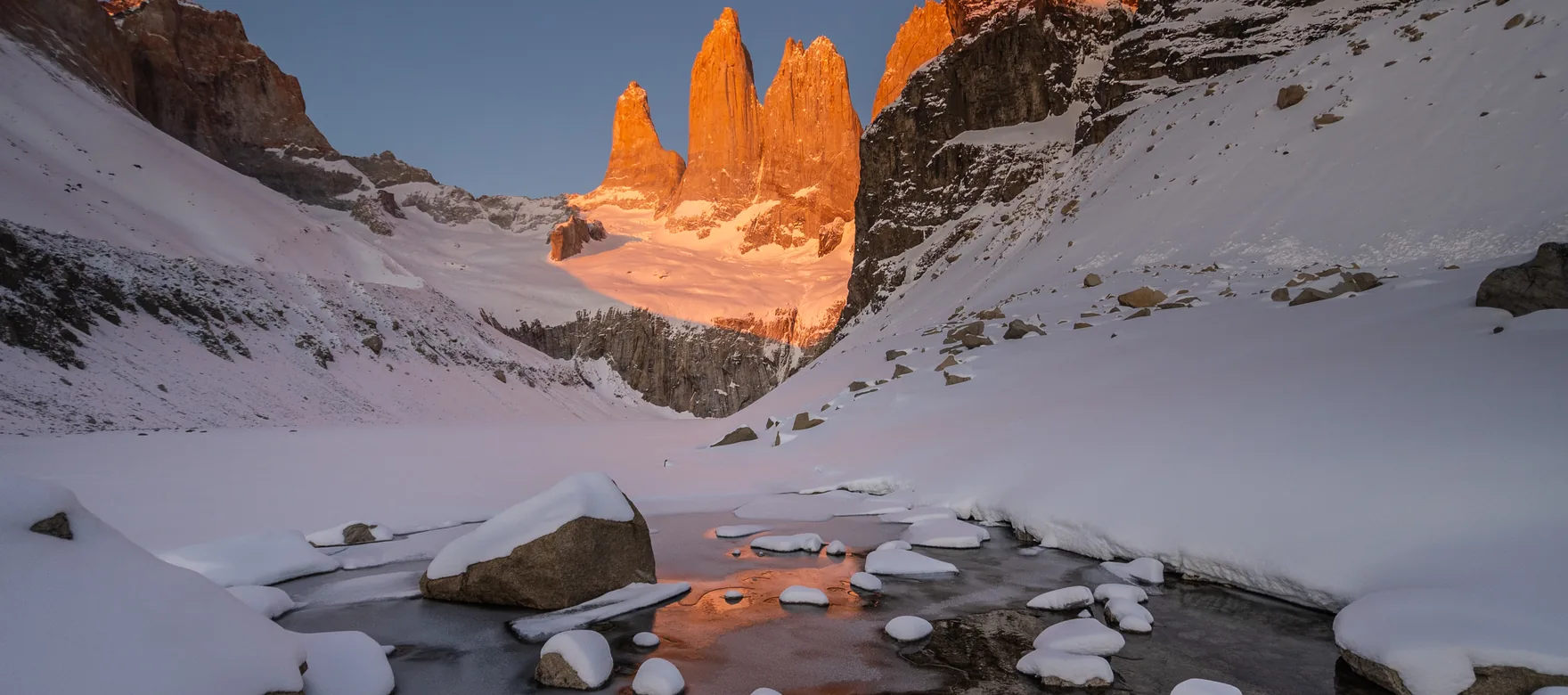 La base de las Torres al amanecer, en pleno invierno: la laguna congelada y la primera luz en las paredes. En julio la máxima media no llega a 0 °C.